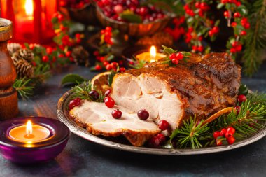 Noel tarzında kızarmış domuz boynu. Koyu lacivert arka plan. Noel aksesuarları. Arka planda mumlar ve fenerler..