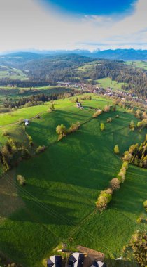 Yukarıdan güzel yeşil çayırlar, uzaktaki Tatra Dağları 'nın karlı zirveleri görünüyor. Havadan bak. İnsansız hava aracından görüntüle.