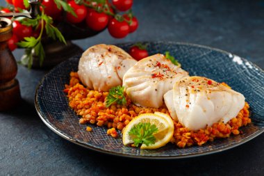 Kızarmış morina filetosu parçaları, kara nohutla servis edilir. Koyu boyalı arkaplan.