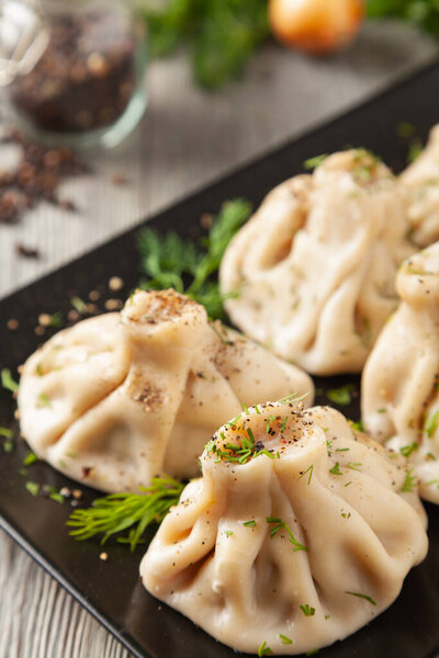 Traditional Georgian dumplings with meat. Khinkali. Served on a plate with traditional Georgian bread. Wooden background. 