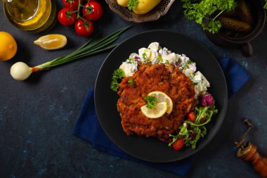 Klasik, geleneksel Viyana sığır filetosu şnitzel. Patates salatasında servis edildi. Üremiş. Koyu arkaplan.