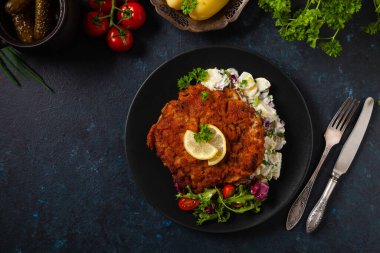Klasik, geleneksel Viyana sığır filetosu şnitzel. Patates salatasında servis edildi. Üremiş. Koyu arkaplan.