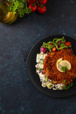 Klasik, geleneksel Viyana sığır filetosu şnitzel. Patates salatasında servis edildi. Üremiş. Koyu arkaplan.