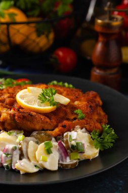 Klasik, geleneksel Viyana sığır filetosu şnitzel. Patates salatasında servis edildi. Üremiş. Koyu arkaplan.