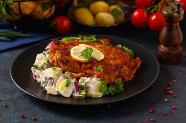 Klasik, geleneksel Viyana sığır filetosu şnitzel. Patates salatasında servis edildi. Üremiş. Koyu arkaplan.