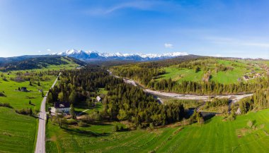 Yukarıdan güzel yeşil çayırlar, uzaktaki Tatra Dağları 'nın karlı zirveleri görünüyor. Havadan bak. İnsansız hava aracından görüntüle.