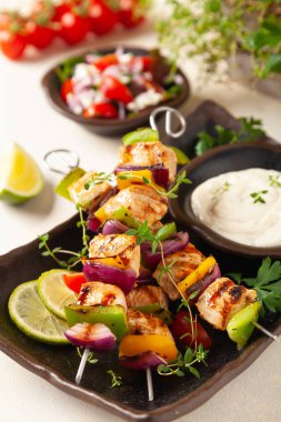 Tavuk, biber ve soğanlı ızgara şiş. Sos ile servis edilir. Boyalı, parlak arkaplan.