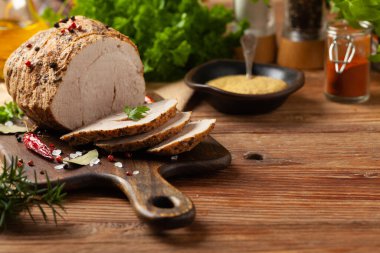 Çıtır, pişmiş jambon. Ahşap bir tahtada baharatlarla servis edilir. Ön görünüm.