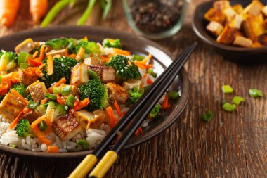 Pilav ve sebzeli soya peyniri. Kahverengi tabakta servis edilir..