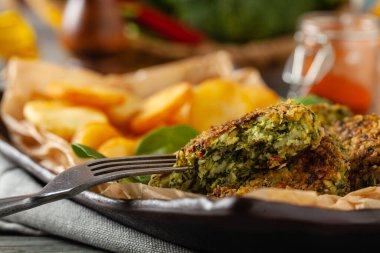 Vejetaryen ıspanak ve brokoli köftesi, kızarmış patatesle servis ediliyor. Ön görünüm.