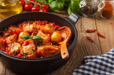 Geleneksel ispanyolca morina balığı. Domates sosunda haşlanmış patates, olivki ve fesleğen ile servis edilmiş. Ön görünüm. 
