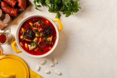Geleneksel İspanyol gulaş çorbası. Fabada Asturiana. Kapaklı sarı kilden bir çömlekle servis edilmiş. Üst görünüm.
