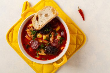 Geleneksel İspanyol gulaş çorbası. Fabada Asturiana. Kapaklı sarı kilden bir çömlekle servis edilmiş. Üst görünüm.