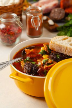 Geleneksel İspanyol gulaş çorbası. Fabada Asturiana. Kapaklı sarı kilden bir çömlekle servis edilmiş. Ön görünüm.