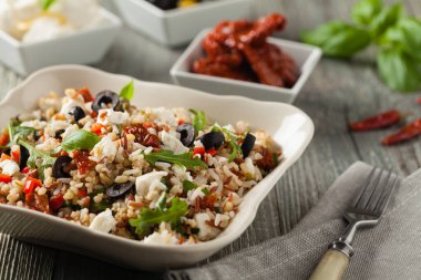 Kırmızı pirinçli moda öğle yemeği, sebze ve sebze karışımı. Ön manzara. Gri ahşap arka planda beyaz kasede servis ediliyor.. 