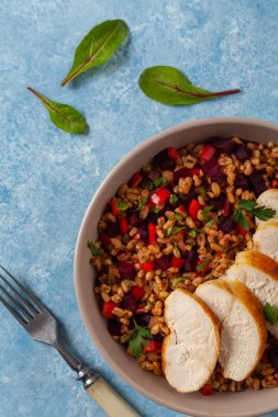 Mısır gevreği, pancar kökü ve tavukla moda bir öğle yemeği. Mavi boyalı arka planda bir kasede servis edilmiş. Üst görünüm. 