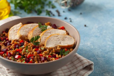 Mısır gevreği, pancar kökü ve tavukla moda bir öğle yemeği. Mavi boyalı arka planda bir kasede servis edilmiş. Ön görünüm. 