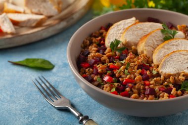 Mısır gevreği, pancar kökü ve tavukla moda bir öğle yemeği. Mavi boyalı arka planda bir kasede servis edilmiş. Ön görünüm. 