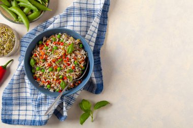 Pirinç ve sebzeli moda öğle yemeği. Mavi bir kasede servis edilmiş, parlak bir arka planda. Üst görünüm.