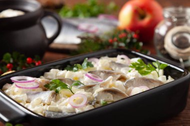 Kremalı ringa salatası ve elma. Siyah bir brikette servis edilmiş. Ahşap arka plan. Noel süslemesi.