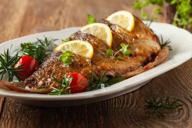 Kızarmış sazan. Beyaz tabakta limon ve vişneli domatesle servis ediliyor. Noel süslemesi. 