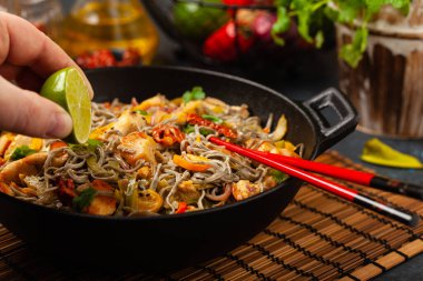 Siyah susamlı buğday eriştesi, tavuk ve sebzeli tavada kızartılmış. Ön görünüm.