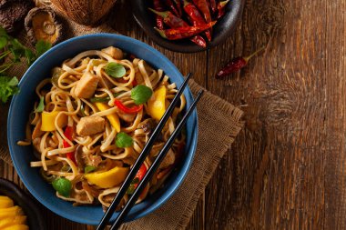 Mangolu kızarmış tavuk ve erişteli hindistan cevizi sütü. Bir tavada hazır. Üst Manzara. Mavi bir kasede servis edildi..