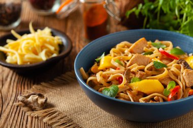 Mangolu kızarmış tavuk ve erişteli hindistan cevizi sütü. Bir tavada hazır. Ön manzara. Mavi bir kasede servis edildi..