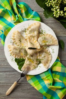 Ispanaklı hamur tatlısı, eritilmiş tereyağı ve doğranmış dereotu serpiştirilmiş. Ahşap arka plan. Beyaz tabak. 