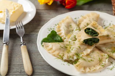 Ispanaklı hamur tatlısı, eritilmiş tereyağı ve doğranmış dereotu serpiştirilmiş. Ahşap arka plan. Beyaz tabak. 