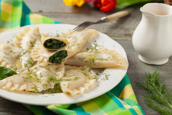 Pierogi Szpinakiem Posypane Stopionym Masłem Posypane Siekanym Koperkiem Drewniane Tło — Zdjęcie stockowe