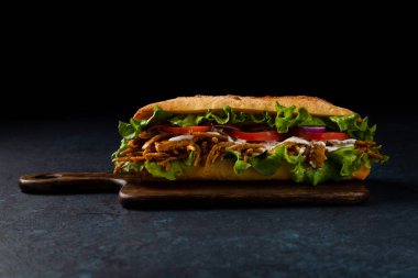 Vejetaryen şam sandviçi. Uzun bir rulo. Kötü ruh hali. Siyah arkaplan.