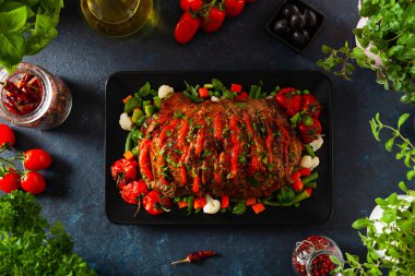 Tam kavrulmuş, domates, zeytin ve domuz boynuyla doldurulmuş. Karanlık arka plan, karanlık ruh hali.