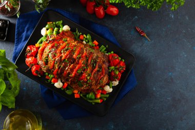 Tam kavrulmuş, domates, zeytin ve domuz boynuyla doldurulmuş. Karanlık arka plan, karanlık ruh hali.