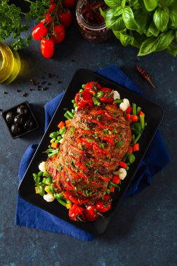 Tam kavrulmuş, domates, zeytin ve domuz boynuyla doldurulmuş. Karanlık arka plan, karanlık ruh hali.