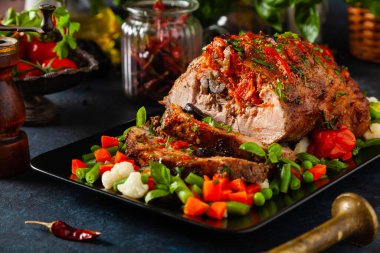 Tam kavrulmuş, domates, zeytin ve domuz boynuyla doldurulmuş. Karanlık arka plan, karanlık ruh hali.