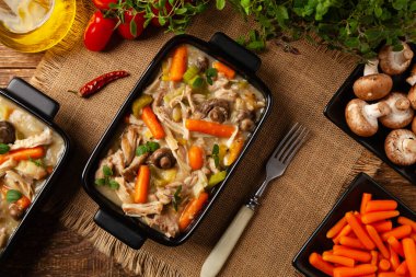 Geleneksel mantar ve sebzeli tavuk güveci. Tavuk güveci. Siyah kaplarda servis edilir..