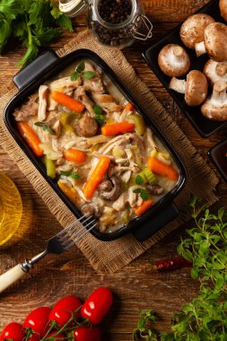 Geleneksel mantar ve sebzeli tavuk güveci. Tavuk güveci. Siyah kaplarda servis edilir..