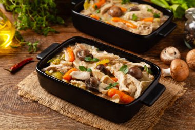 Geleneksel mantar ve sebzeli tavuk güveci. Tavuk güveci. Siyah kaplarda servis edilir..