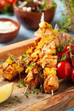 Somon ve ananaslı ızgara şiş kebap. Yoğurt sosuyla servis edilir. Mavi boyalı arkaplan.