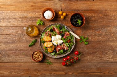 Salad with burrata cheese and croutons. Wooden background.