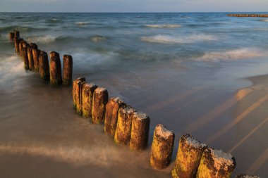 Wooden breakwater in the waters of the Baltic Sea. The sunset. Long exposure time.
