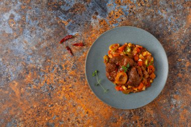 Ossobuco haşlanmış sebzelerle servis edilir. Renkli bir geçmiş. Gri tabak.