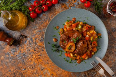 Ossobuco haşlanmış sebzelerle servis edilir. Renkli bir geçmiş. Gri tabak.