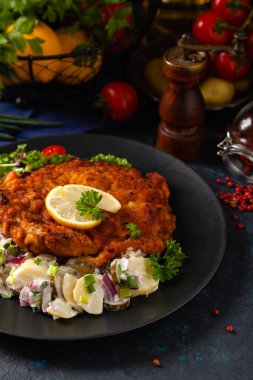 Klasik, geleneksel Viyana sığır filetosu şnitzel. Patates salatasında servis edildi. Üremiş. Koyu arkaplan.