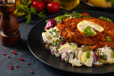 Klasik, geleneksel Viyana sığır filetosu şnitzel. Patates salatasında servis edildi. Üremiş. Koyu arkaplan.