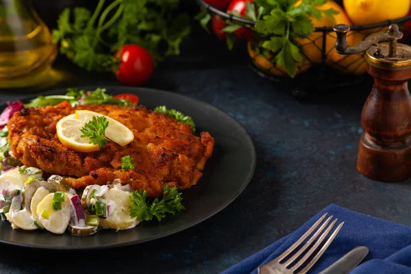 Klasik, geleneksel Viyana sığır filetosu şnitzel. Patates salatasında servis edildi. Üremiş. Koyu arkaplan.