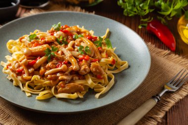 Shimeji mantarlı ve tavuklu geleneksel erişte. Bir tavada hazır. Gri bir tabakta servis edilmiş. Ahşap arka plan. Ön görünüm.