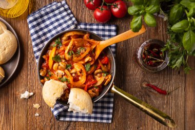 Chicken stew with peppers, mushrooms and tomatoes. Wooden background. 
