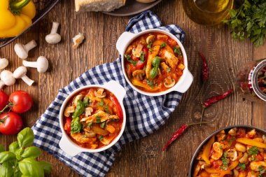 Chicken stew with peppers, mushrooms and tomatoes. Wooden background. 